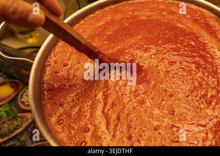 Hausgemachte Tomatensauce in einem großen Topf mit Holzlöffel Stockfoto