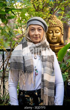 Reife Frau, die neben einer Buddha-Statue steht Stockfoto