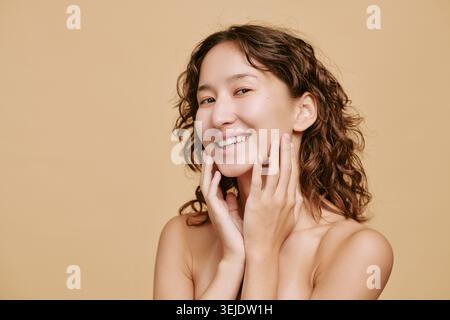 Porträt einer asiatischen Erwachsenen-Frau, die das Gesicht für die Skincare-Kampagne berührt Stockfoto