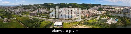Panoramablick auf die Drohne mit Blick auf die äußere Ringstraße von Tirana, Wohngebäuden am See und sanften grünen Hügeln unter hellem Himmel. Stockfoto