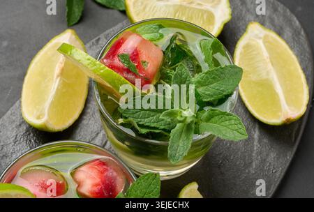 Erfrischender Mojito-Cocktail mit Limette, Minze, Erdbeere und Eis auf dunklem Hintergrund, Blick von oben Stockfoto