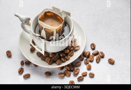 Tropfe Kaffeebeutel mit gemahlenem Kaffee in einer Tasse Stockfoto