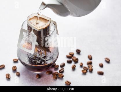 Gießen Sie Wasser in gemahlenen Kaffee, Kaffeebeutel und Glas Stockfoto