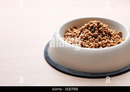 Eine Schüssel Hundefutter auf einem Holzboden. Stockfoto