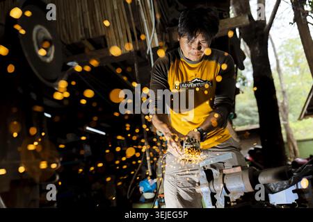 Konzentrierter Handwerker, Arbeiter, der Metall mit Werkzeug in einer Industriehalle schleift. Konzentrierte Arbeit erzeugt einen Schauer heller Funken vom leistungsstarken mac Stockfoto