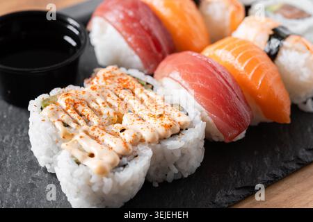 Verschiedene Sushi-Auswahl und Sojasauce auf Schiefertablett auf Holztisch Stockfoto