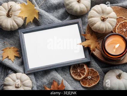 Herbstkomposition. Fotorahmen, Kürbisse, getrocknete Blätter auf grauem gestricktem Hintergrund. Herbst, Herbst, halloween, Thanksgiving-Verborgenheit Stockfoto