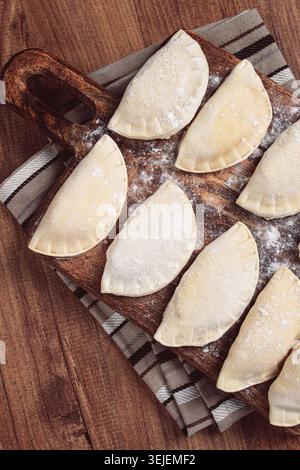 Traditionelles polnisches Gericht, Teigtaschen, roh, gefroren, auf einem Schneidebrett, Holztisch, Blick von oben, keine Leute, Stockfoto