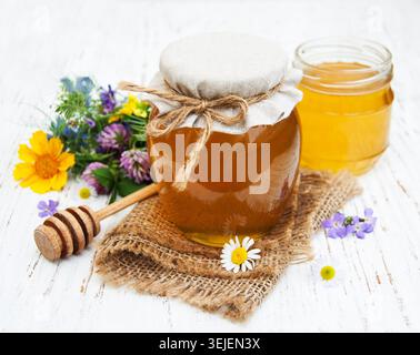 Honig und wilde Blumen auf hölzernem Hintergrund Stockfoto
