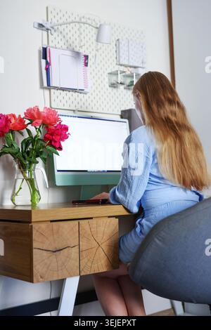 Blonde Frau genießt Kaffeepause während der Arbeit von zu Hause aus, modernes Lifestyle-Porträt mit gemütlichem Arbeitsplatz und femininer Atmosphäre. Stockfoto