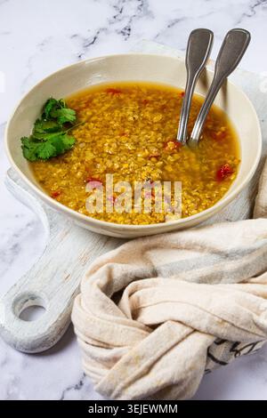 Warme und angenehme Linsensuppe mit Kräutern und Gewürzen, serviert in einer Schüssel auf einem hölzernen Schneidebrett Stockfoto