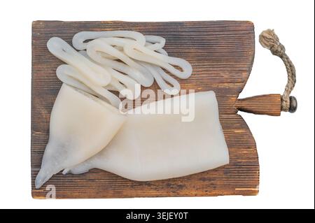 Frische Tintenfischröhren und Ringe auf einem rustikalen Holzbrett mit Kräutern schaffen eine saubere Meeresfrüchte-Komposition, die sich ideal für kulinarische Themen und Marktthemen eignet. Stockfoto