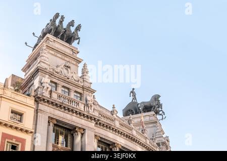 Madrid, Spanien - 30. November 2021: Nahaufnahme des Banco de Bilbao-Gebäudes in Madrid. Komplizierte Skulpturen und atemberaubende Quadriga-Statuen auf dem Dach Stockfoto