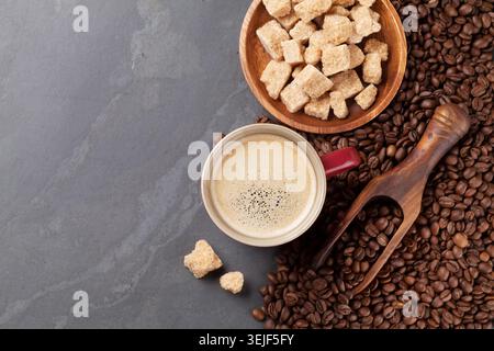 Tasse Kaffee, Bohnen und braunem Zucker am Steintisch Stockfoto