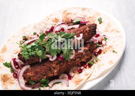 Lula Kebab, auf Lavash, mit roten Zwiebeln, Granatapfel und Sumak, Draufsicht, Nahaufnahme, horizontal, keine Personen, Stockfoto