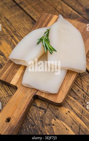 Saubere Tintenfischröhrchen mit Kräutern auf strukturierter Holzoberfläche, ideal für Gourmet-Meeresfrüchte-Kochzwecke und für Fotofotos. Stockfoto