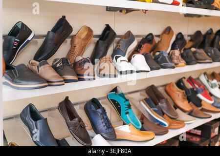 Lederschuhe für Herren werden in Holzregalen im Schuhgeschäft ausgestellt. Geeignet für Modeschuhmarken, Schuhgeschäfte für Herren und Einzelhandelsinhalte. Stockfoto