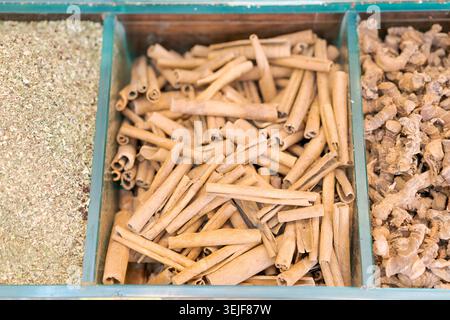 Zimtstangen und getrockneter Ingwer in Holzkiste auf dem Gewürzmarkt. Geeignet für Bio-Gewürzmarken, Kräuterkochen und kulinarische Inhalte. Stockfoto