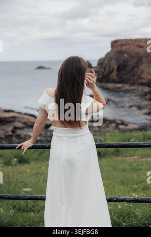 Die Frau steht am Meer und blickt auf den Horizont Stockfoto