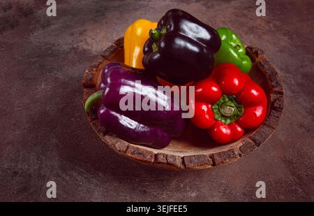 Eine Sammlung von bunten Paprika, in einer Holzschale, auf einer dunklen Oberfläche, Blick von oben, keine Leute Stockfoto