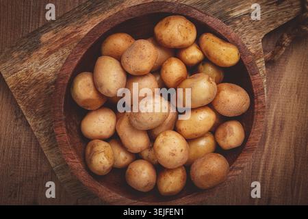 Frisch geerntete kleine Kartoffeln in einer Holzschale auf einer rustikalen Oberfläche mit natürlichen Texturen und Farben Stockfoto