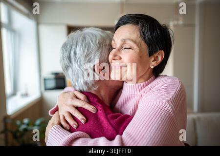 Glückliches älteres Paar, das sich herzlich umschließt. Fröhliche Frau umarmt Ehemann und feiert gute Nachrichten in der Familie Stockfoto
