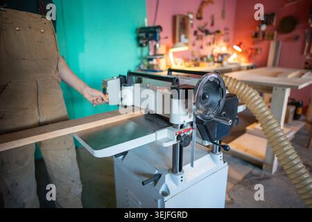 Erfahrener Handwerker, der mit Holz an Hobeldickengelenken arbeitet, Möbelmaterialien vorbereitet Stockfoto