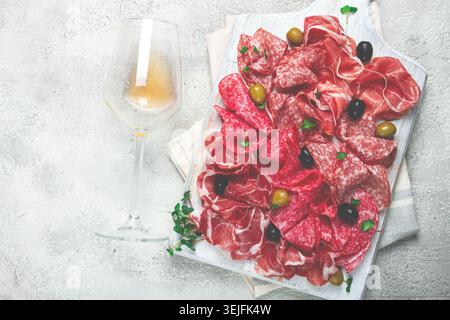 Gemischte Fleischvorspeise, Schinken, Salami und Schinken, mit Oliven, auf einer weißen Holztafel, heller Hintergrund, Frühstück, Top VI Stockfoto