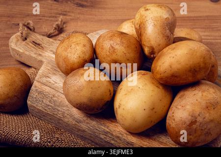 Rohe Kartoffeln, verstreut auf einem Schneidebrett, Nahaufnahme, keine Leute, Stockfoto