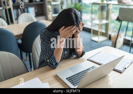 Burnout-Konzept. Asiatische Geschäftsfrau, die die Stirn berührt, Kopfschmerzen langweiliger Job und müde emotionale Schmerzen und professionelle per Stockfoto