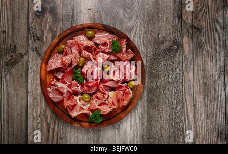 Auswahl , Fleischvorspeise in Scheiben, Prosciutto, Salami und Schinken, mit Oliven, auf einem Holzbrett, Frühstück, Blick von oben, Nahaufnahme, n Stockfoto