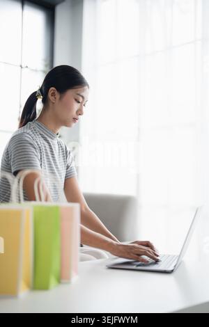 Asiatische Frau hält Handy mit Smartphone für Online-Shopping mit Verkaufstaschen. Konsum Lifestyle Co Stockfoto