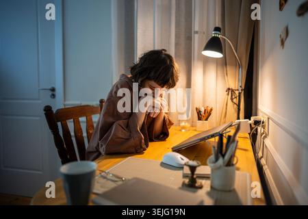 Müde Frau ruht Kopf auf Handflächen nach Laptoparbeit in der späten Stunde. Müdigkeitsproblem junger Schüler Stockfoto