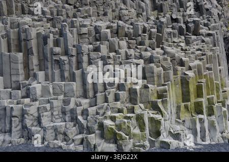 Eine detaillierte Vollformatansicht einer geometrischen Wand aus ineinander greifenden sechseckigen Basaltsäulen mit natürlichen geologischen Texturen. Stockfoto