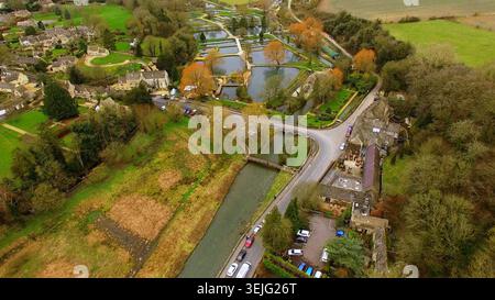 4K-Drohnenansicht von Bibury, England. Malerische Landschaft von Cotswolds mit dem Fluss Coln, historischen Steinhäusern und Teichen der Forellenzucht. Stockfoto