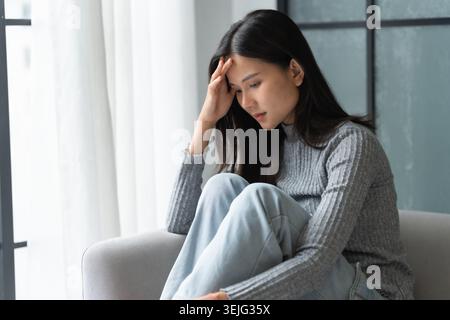 Junge asiatische Frau fühlt sich einsam traurig krank gestresst auf Sofa zu Hause allein für Healthcare Wellness Lifestyle. Stockfoto