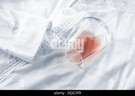 Glas, mit rosafarbenem Wein, verschüttet auf einem weißen Hemd, Nahaufnahme, selektiver Fokus, keine Leute, Konzept, Draufsicht, Stockfoto