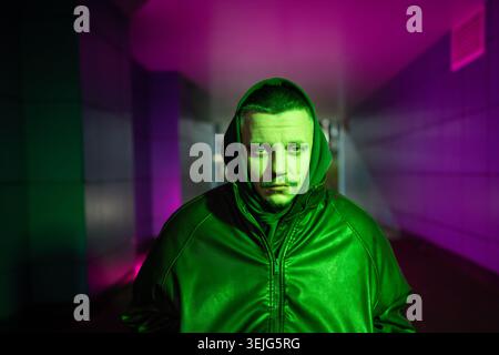 Deprimierter behinderter Mann im Rollstuhl in Farbe Neon rgb Licht, das psychische Probleme darstellt. Stockfoto