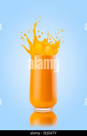 Frischer Mangosaft - helle fliegende Tropfen und Spritzer Saft im Glas auf blauem Hintergrund. Gesundes Bio-Getränk für die Detox-Diät Stockfoto