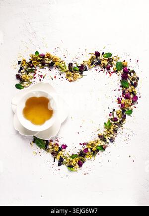Tee-Set, Herzform, mit einer Tasse, Draufsicht, auf weißem Hintergrund, Rosenknospen, Jasmin, Blau, Chrysantheme, Minzblätter, Stockfoto