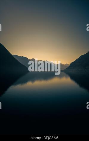 Dämmerung über dem Idro-See in Norditalien, mit ruhigem Wasser, Bergsilhouetten und Reflexionen unter einem verblassenden Abendhimmel. Stockfoto