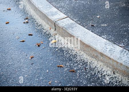 Gefrorene Straße mit Chemikalien und technischem Salz gegen Eisbildung in der kalten Wintersaison bestreut. Stockfoto