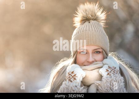 Porträt der jungen süßen Frau am sonnigen Wintertag. Eine Frau in warmen Kleidern lächelt und blickt in die Kamera Stockfoto