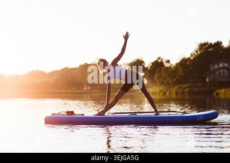 Eine Frau, die Yoga auf dem Sup Board macht Stockfoto