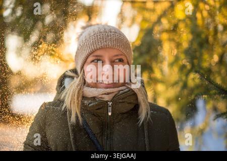 Junge Frau in warmen Kleidern träumt, lächelt, genießt Spaziergänge am sonnigen Wintertag Stockfoto