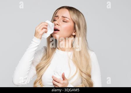 Ungesunde Frau mit Papierserviette niesen, erlebt Allergiesymptome, verfing eine Erkältung, geschlossene Augen Stockfoto