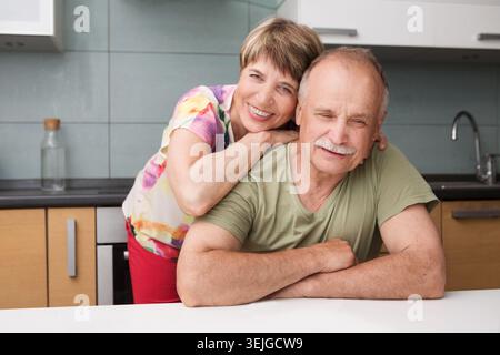 Glückliches und lächelndes Seniorenpaar, das verliebt ist und sich in die Küche umschließt. Stockfoto