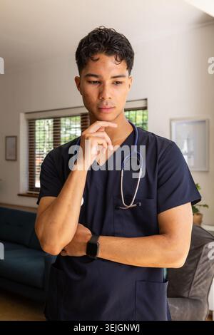 Asiatischer männlicher Arzt, der Stethoskop beim Prüfen der Smartwatch im Wohnzimmer anpasst. Medizinisches Personal, Gesundheitswesen, PR Stockfoto