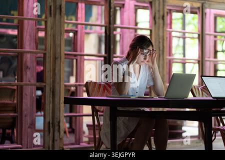 Müde oder gelangweilt kaukasische Arbeiterin oder Studentin sitzen am Schreibtisch brauchen Ruhe leiden an Müdigkeit Stockfoto