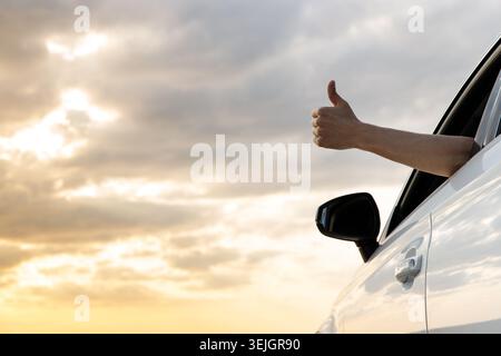 Ein Mann zeigt Daumen hoch, macht ein OK-Schild mit der Hand vom Autofenster Stockfoto